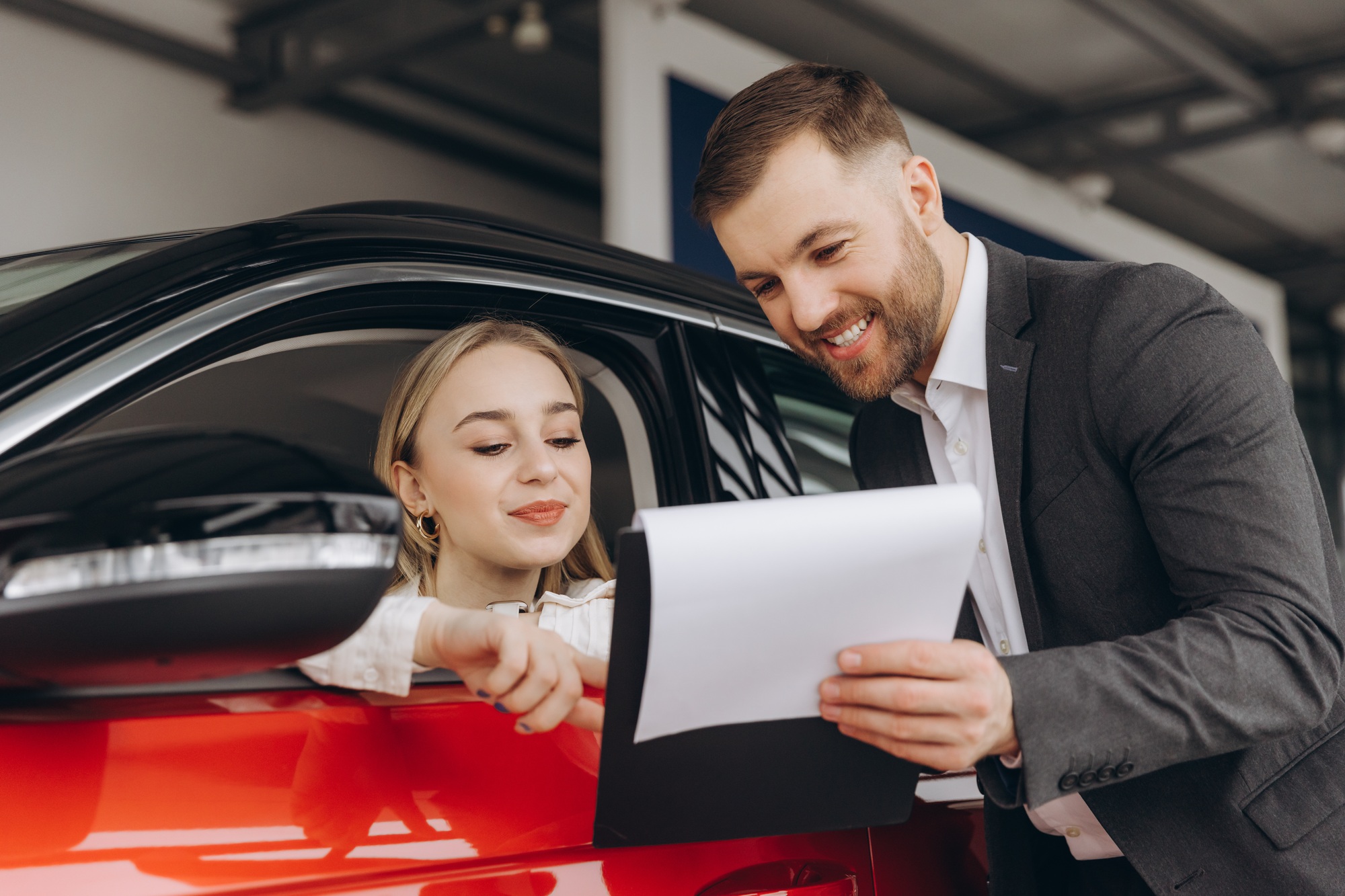 Happy woman with car dealer in auto show or salon. Car Sales Manager Showing Auto