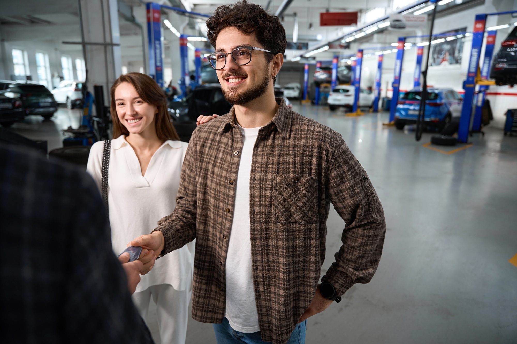 Sales person giving keys of new car to happy man couple satisfied to buy auto